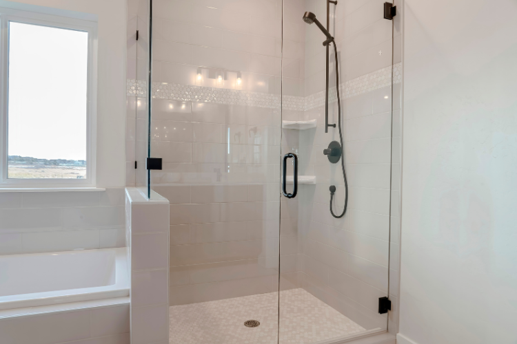 Frameless shower door with black hardware installed next to a bathtub