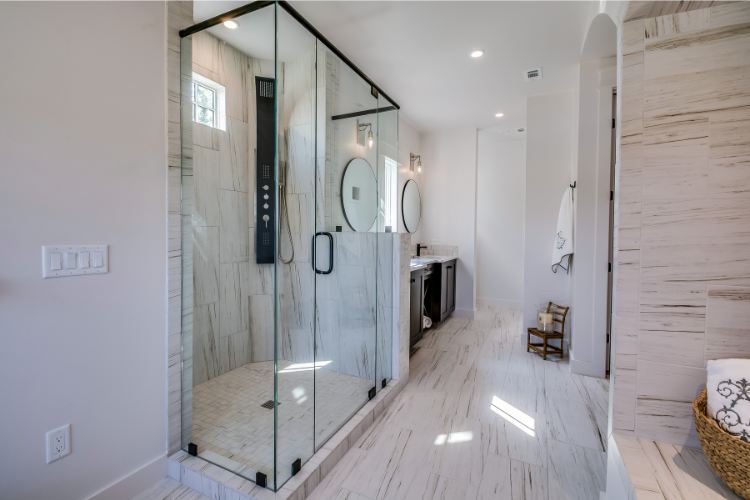 Large frameless shower door in a modern marble bathroom before removal