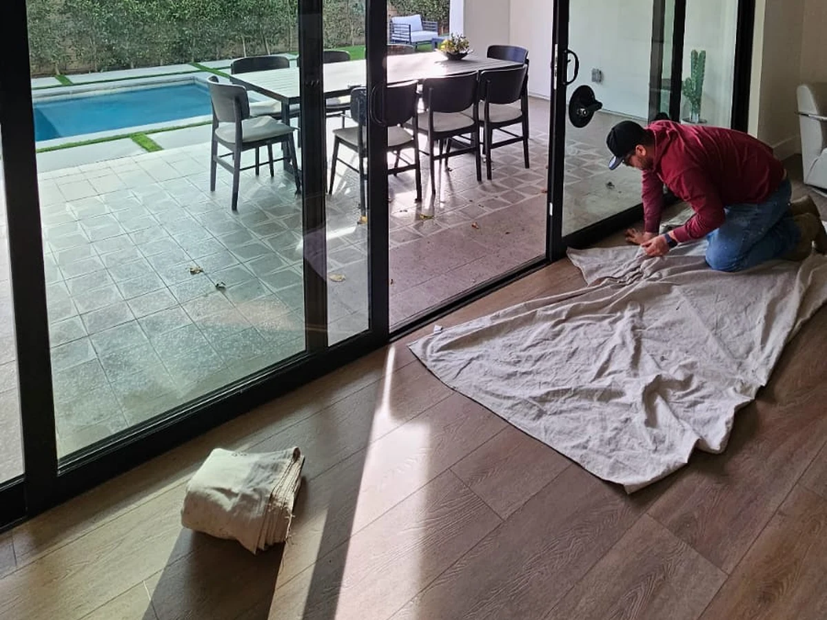 JDM technician laying drop cloths on the floor in front of a multi panel sliding glass door before removing it