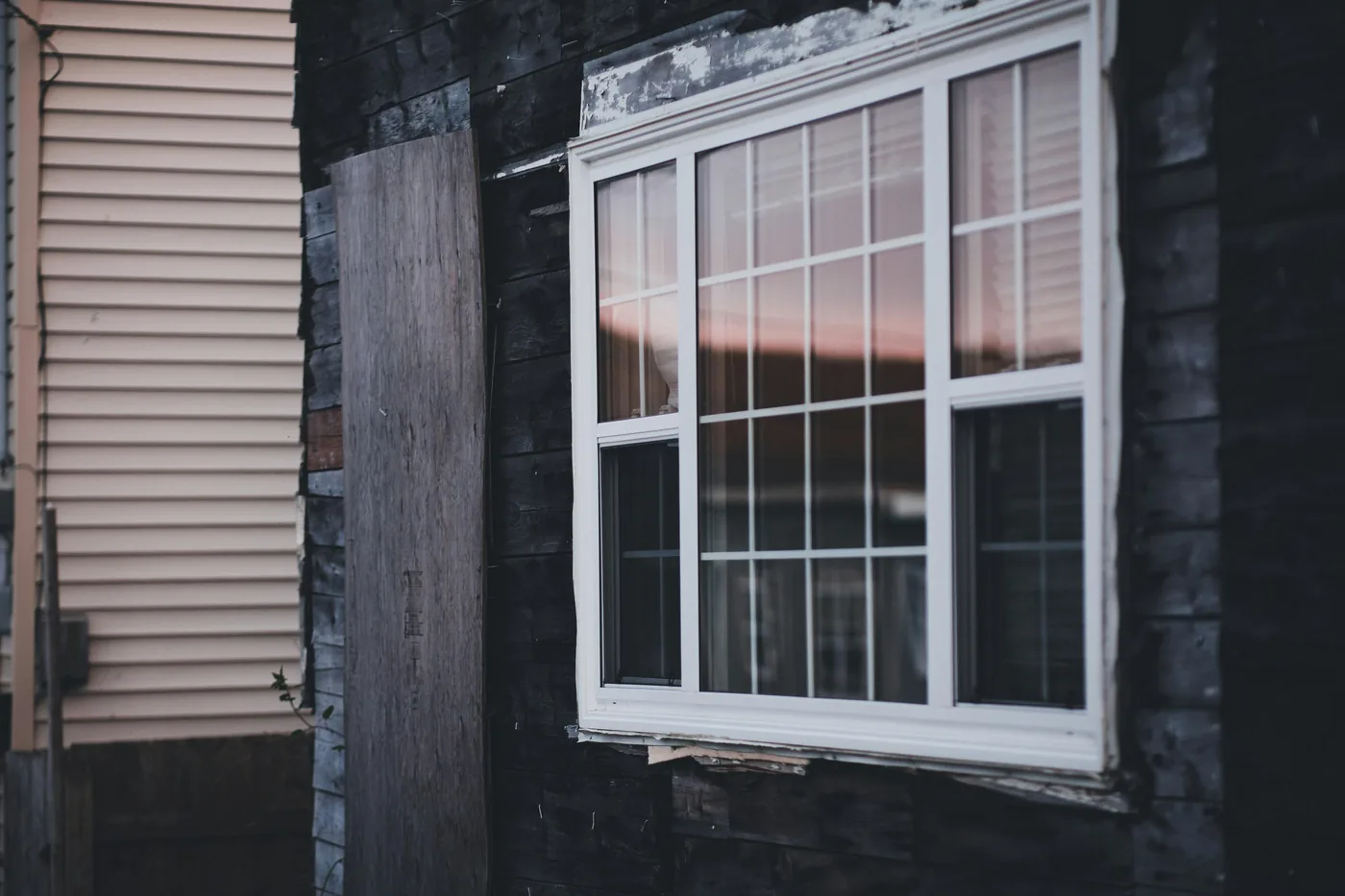 Older wood-sided home with a worn white-framed window, the kind of existing opening that drives up prep cost on a Broward retrofit