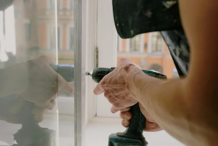Window repair technician using a drill on a window frame in a Fort Lauderdale home