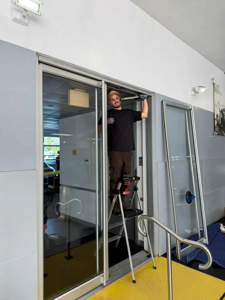 JDM technician repairing a commercial storefront sliding glass door in Colorado